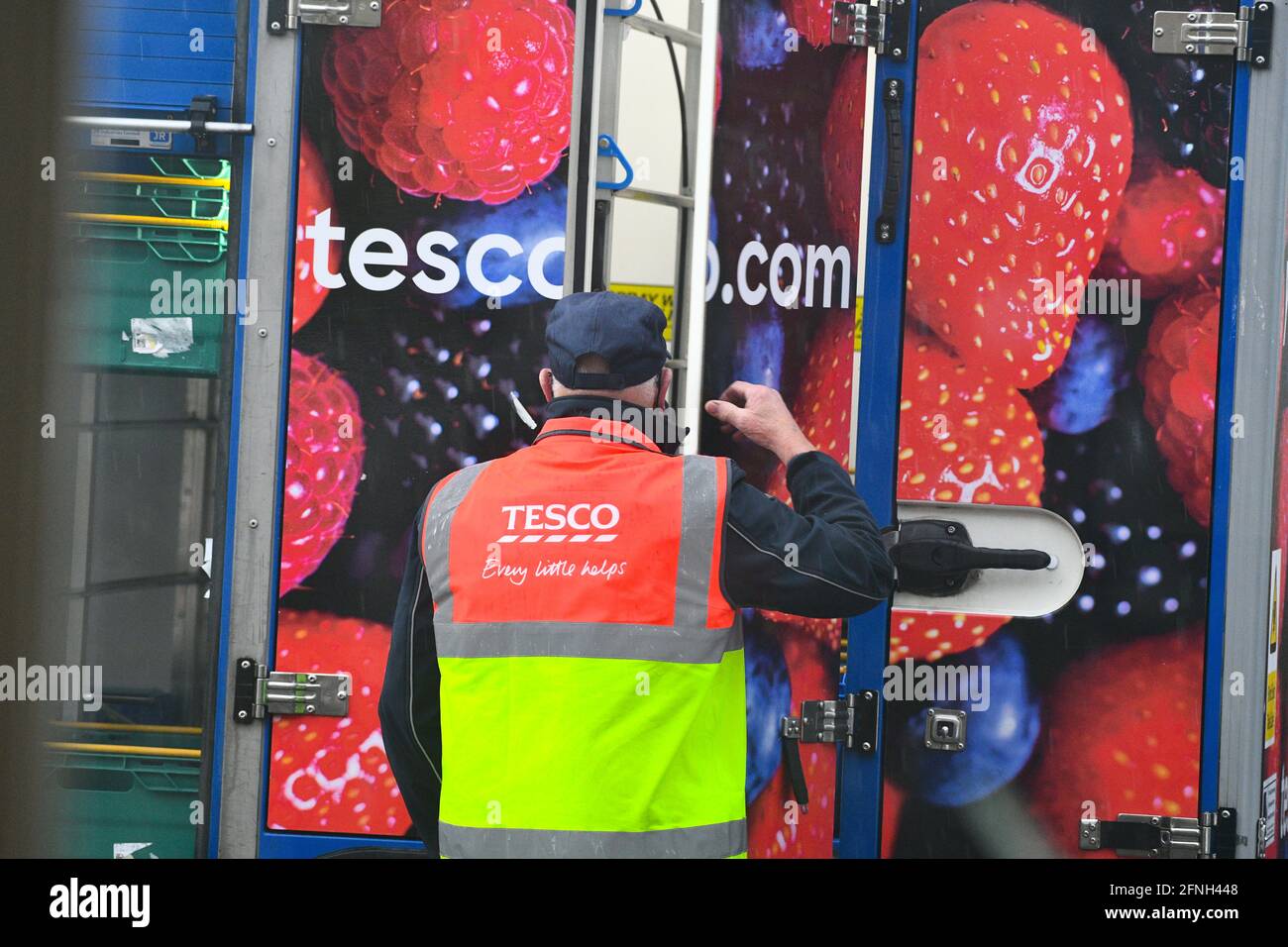 A older looking Tesco Home Delivery driver, pictured getting shopping from his delivery vehicle  to drop food off to Tesco internet shopping customers homes. Stock Photo