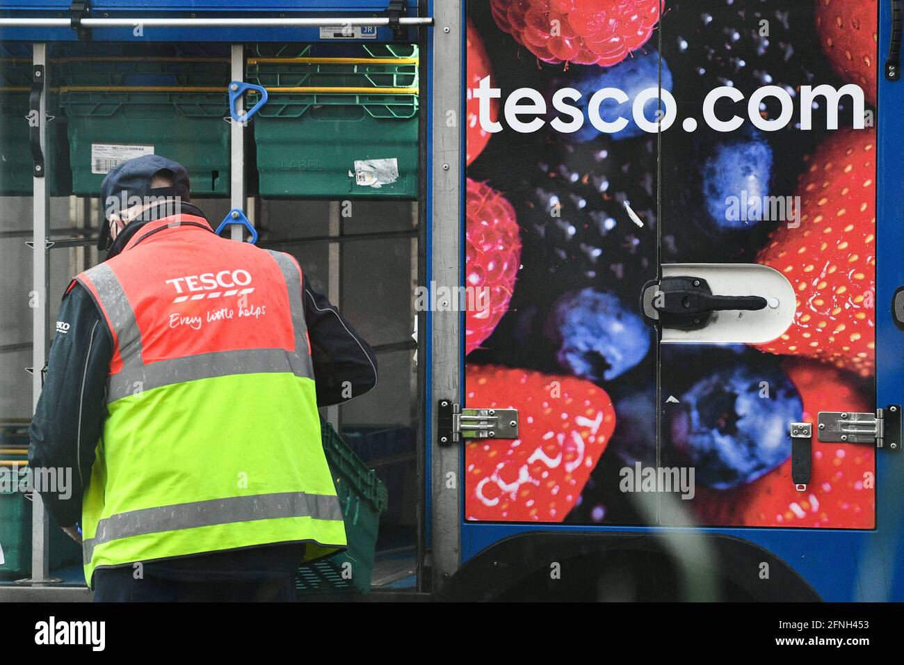 A older looking Tesco Home Delivery driver, pictured getting shopping from his delivery vehicle  to drop food off to Tesco internet shopping customers homes. Stock Photo