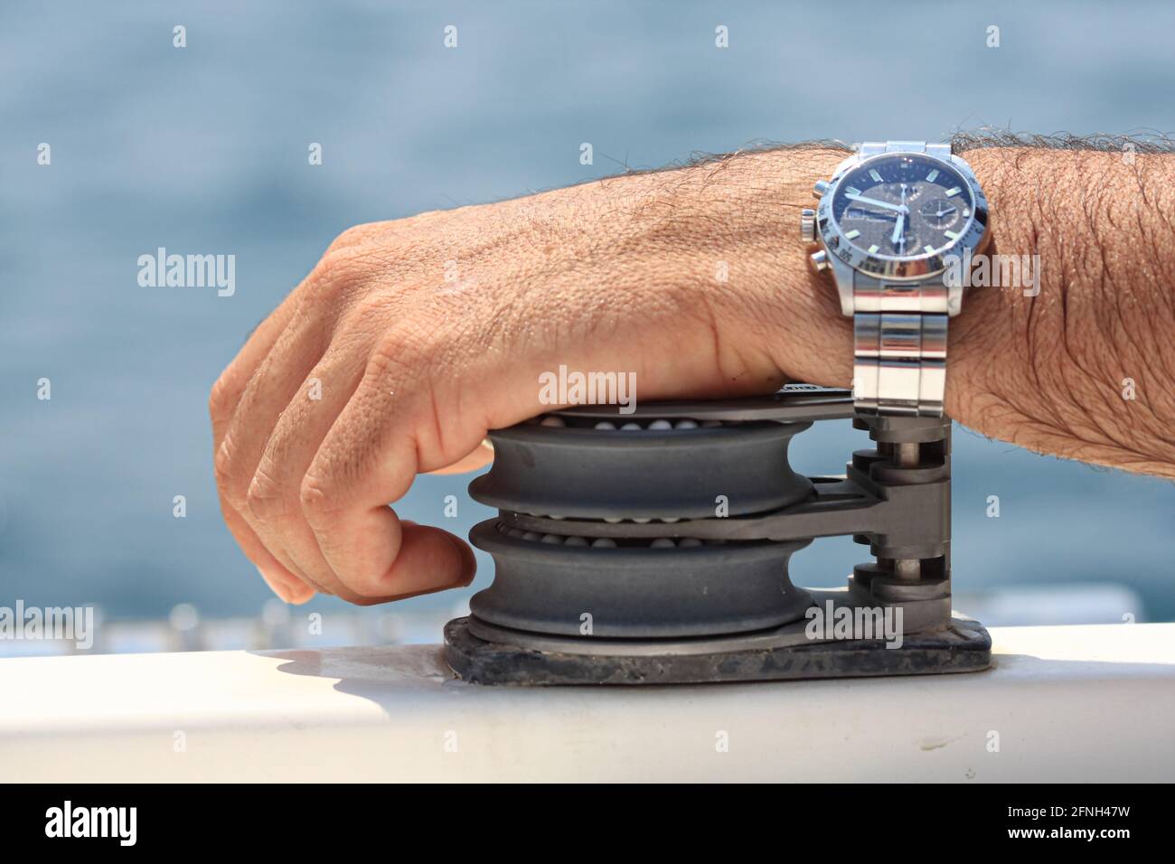 Sailor hand leaning on a winch of a sailing boat. Stock Photo