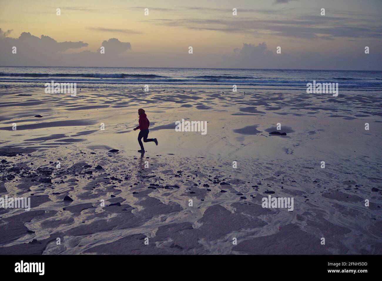 silhouette of Woman running on Porthmeor beach at sunset Stock Photo