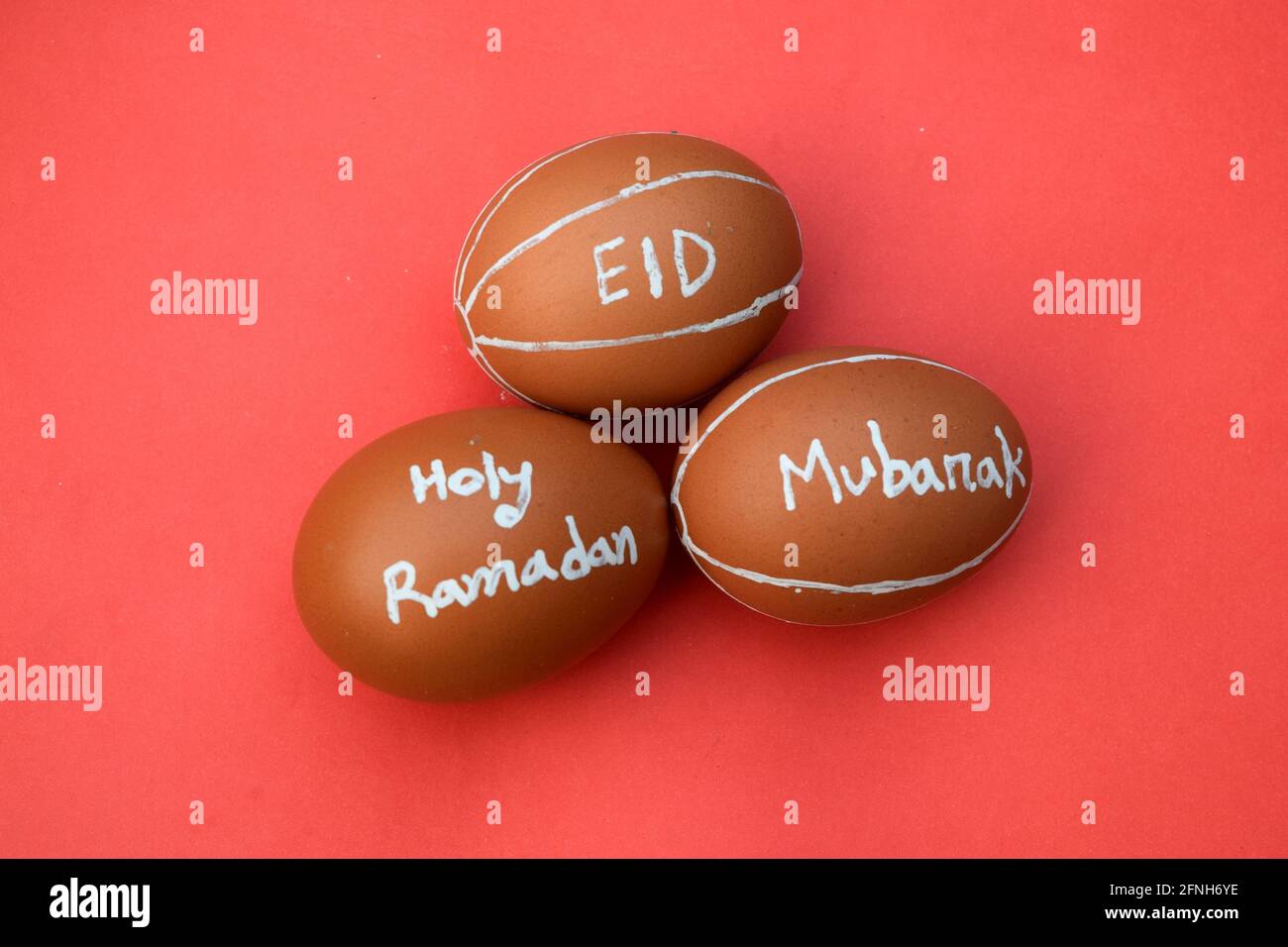 Holy Ramadan and Eid Mubarak hand typography on the egg. Red isolated background. Stock Photo