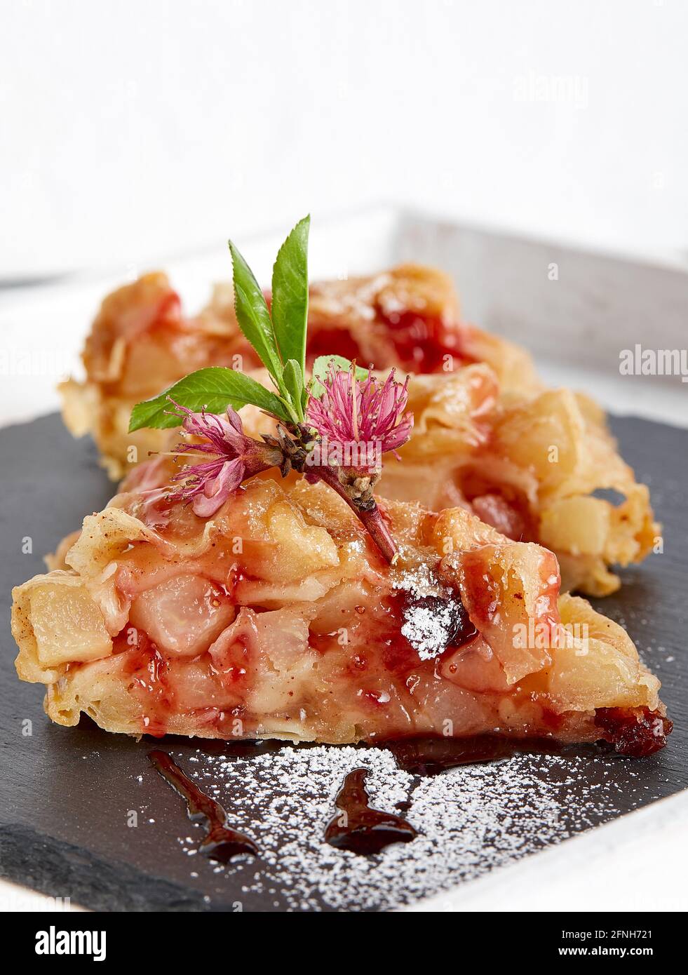 Pie strudel slices on a piece of slate decorated with freshapple flowers and leaves and icing sugar Stock Photo