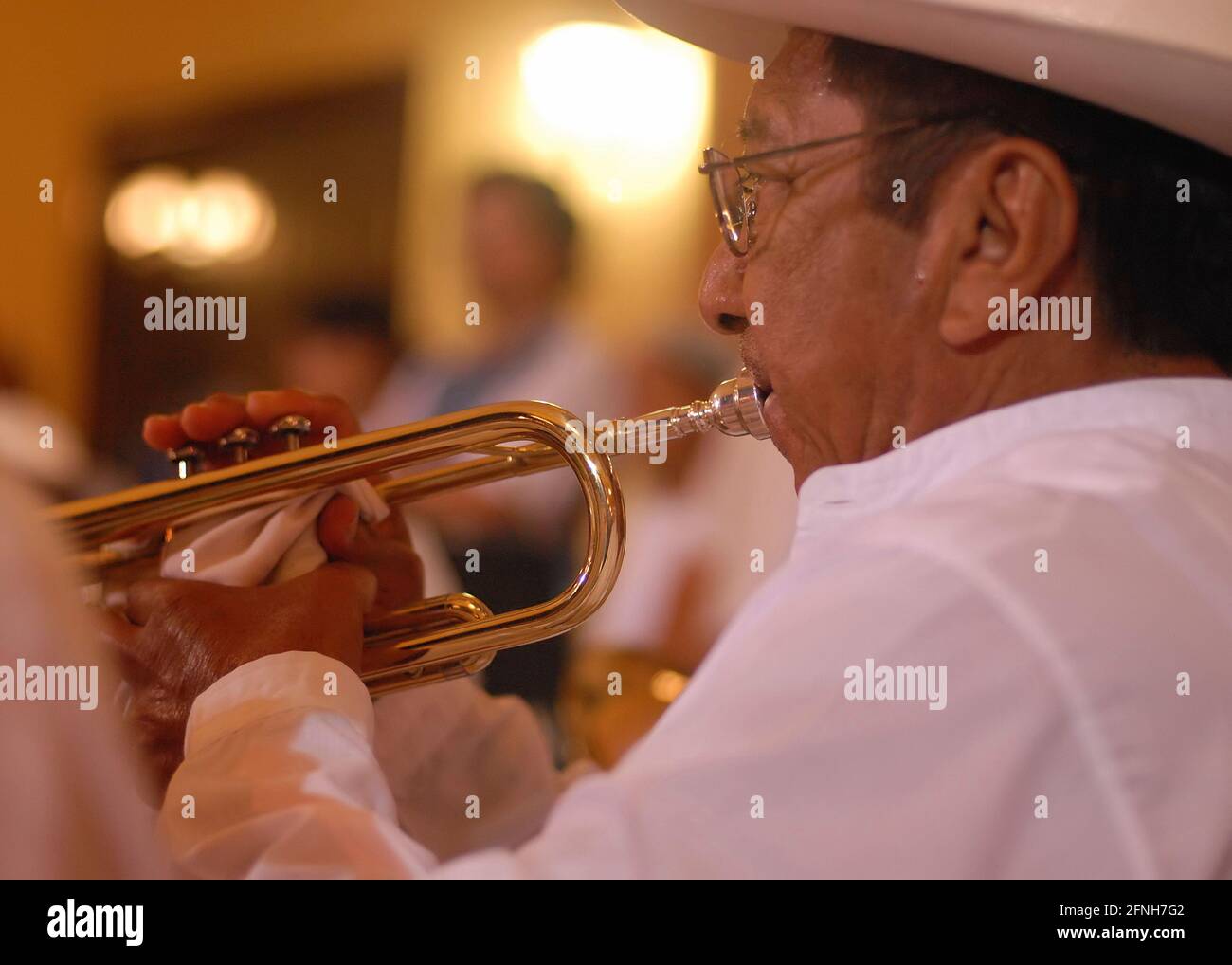 A musician playing a trumpet rear view. Shallow focus on the foreground hand and face with the rest of the section falling into the blur of the backgr Stock Photo