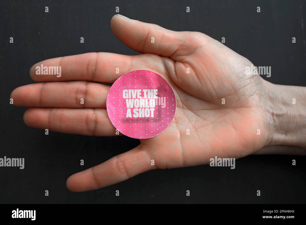 on an asian female hand, a give the world a shot sticker advocating global rollout of the covid 19 vaccine Stock Photo
