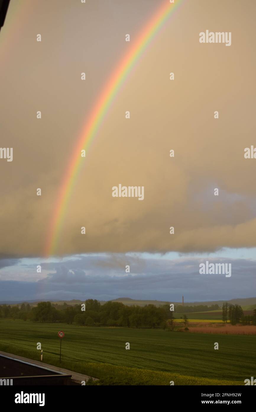 huge rainbow in front of dark clouds Stock Photo