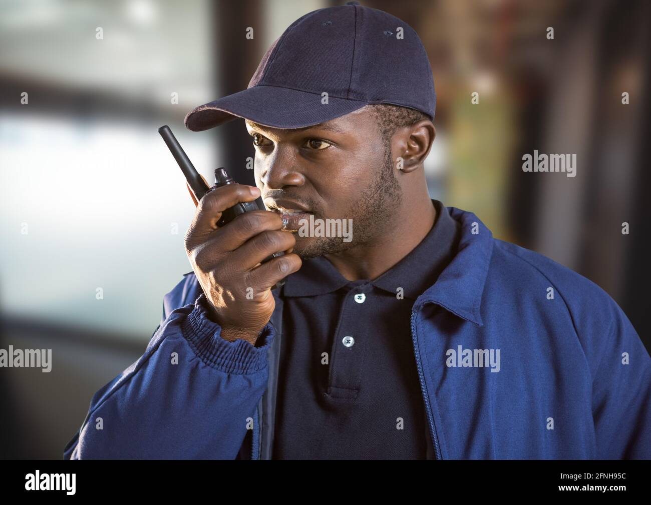 Composition of male security guard using walkie talkie over blurred  background Stock Photo - Alamy