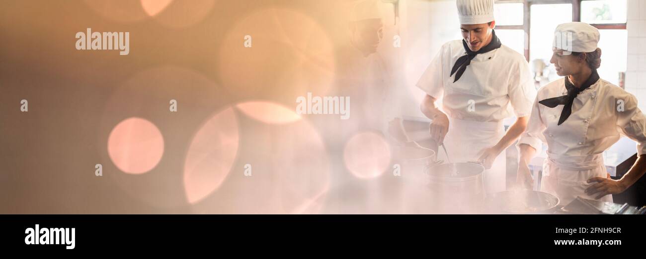 Composition of male and female chefs in kitchen with spots of light Stock Photo