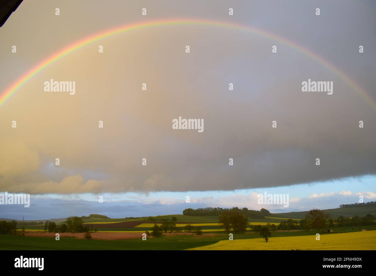 huge rainbow in front of dark clouds Stock Photo