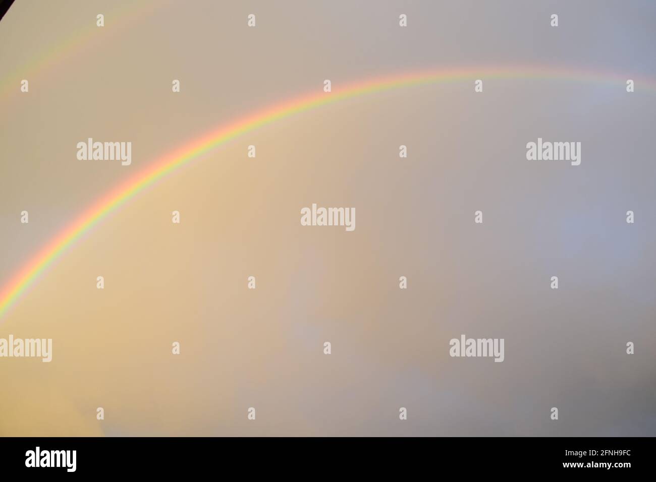 huge rainbow in front of dark clouds Stock Photo