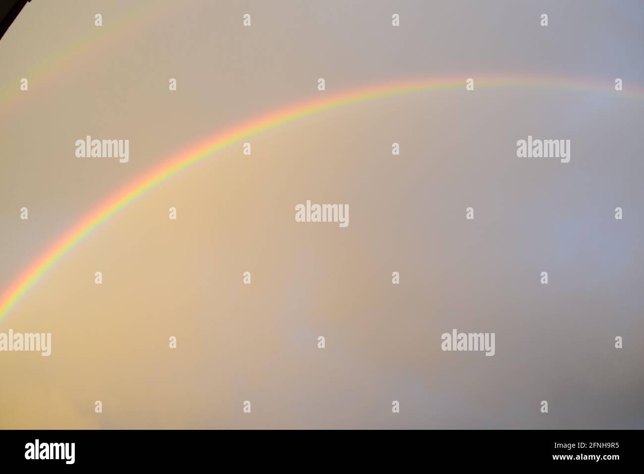 huge rainbow in front of dark clouds Stock Photo
