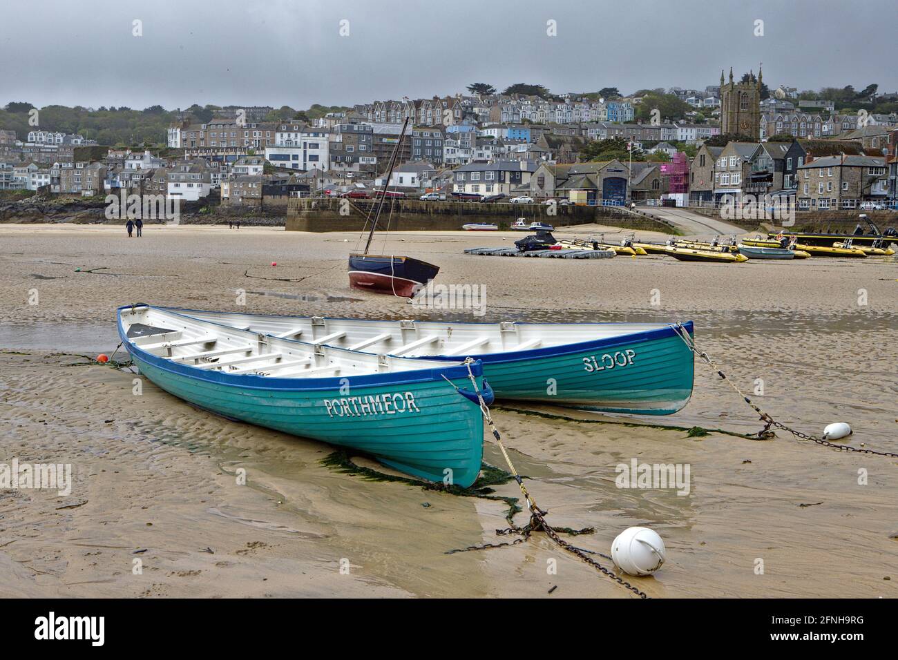 two turquoise boats stranded at low tide in St Ives harbour Stock Photo