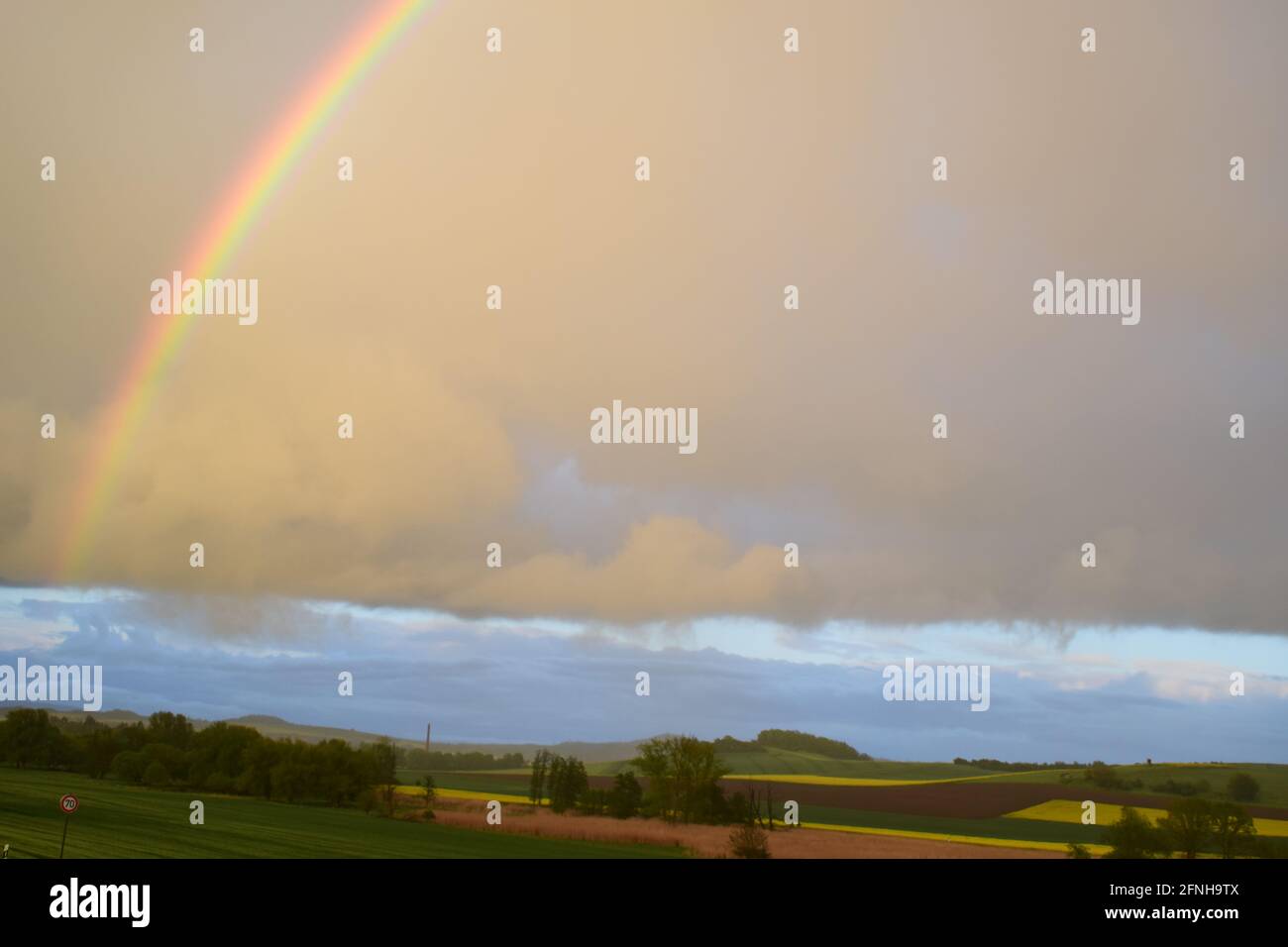 huge rainbow in front of dark clouds Stock Photo