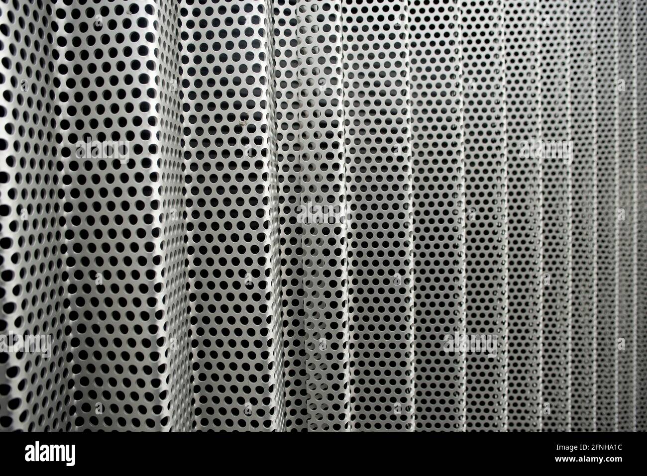Perforated thick stainless steel cladding sheets bent sharply to form a