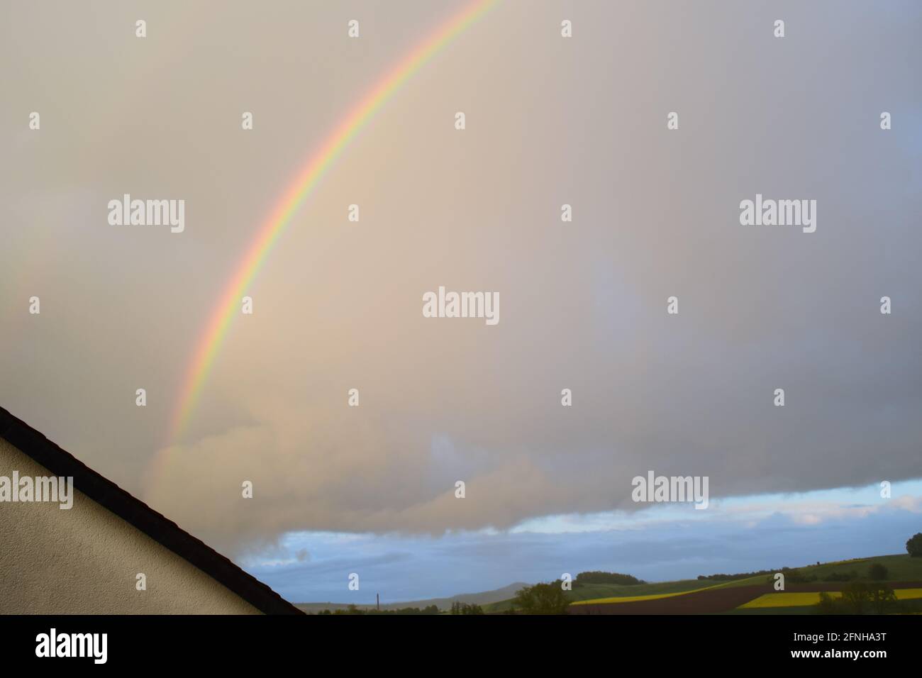 huge rainbow in front of dark clouds Stock Photo
