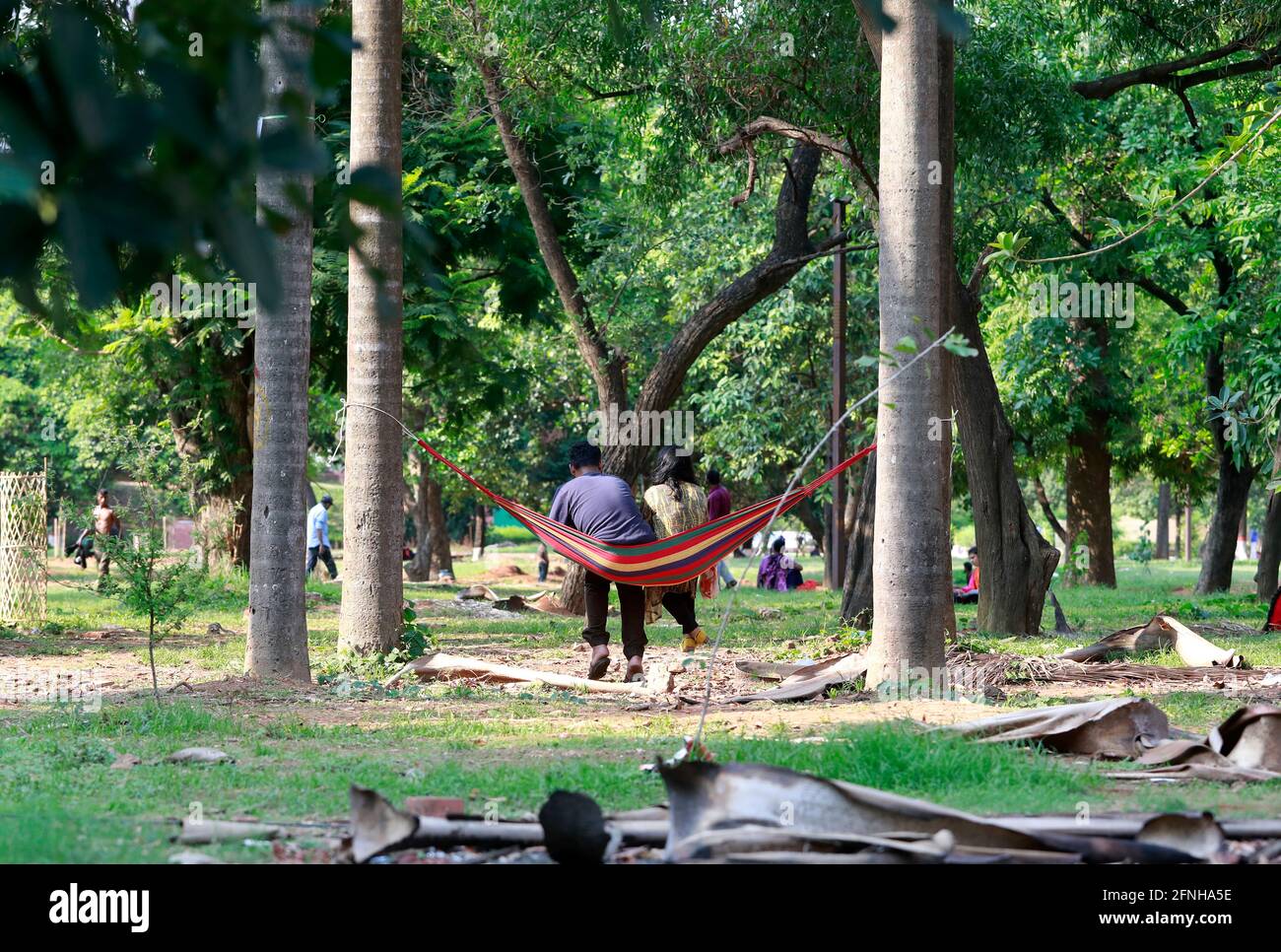 Dhaka, Bangladesh - May 17, 2021: It is summer in Bangladesh so for a little relief, a couple is sitting on a hammock with two trees at Suhrawardy Udy Stock Photo