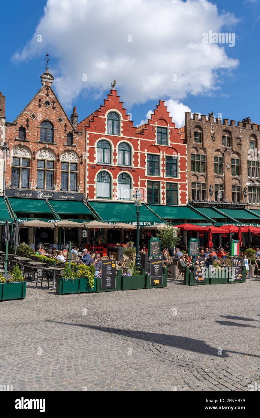 Bruges, Belgium - 12 May, 2021: people enjoy a day out in the restaurants on Market Square in Bruges with many historic brick buildings in the backgro Stock Photo