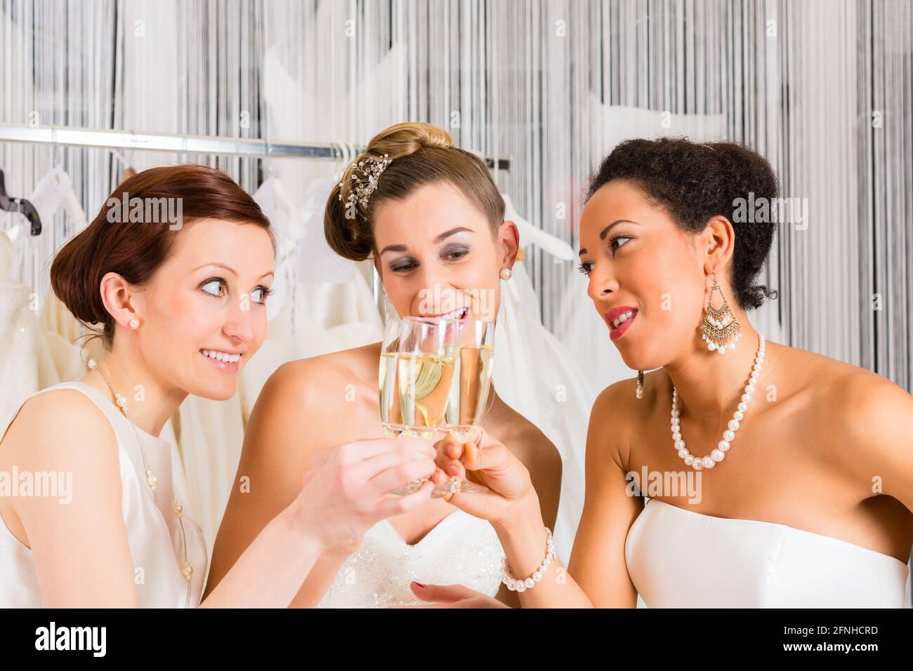 Women drinking champagne while bridal gown fitting in wedding fashion store Stock Photo