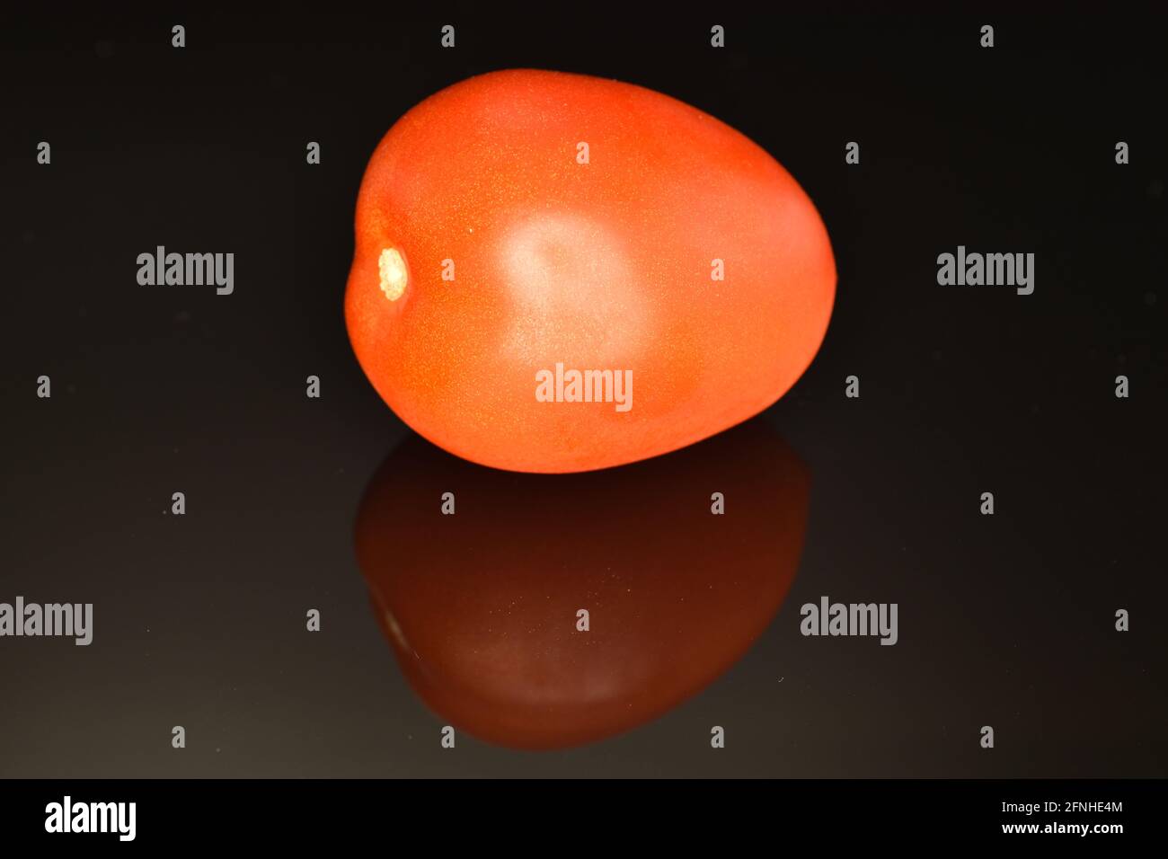 One red tomato, close-up, on a black background. Stock Photo