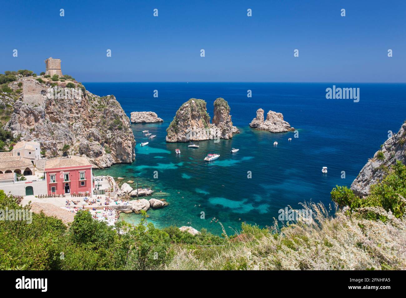 Scopello, Trapani, Sicily, Italy. View over rocky cove to the Faraglioni, a series of stacks in the Gulf of Castellammare off the Tonnara di Scopello. Stock Photo