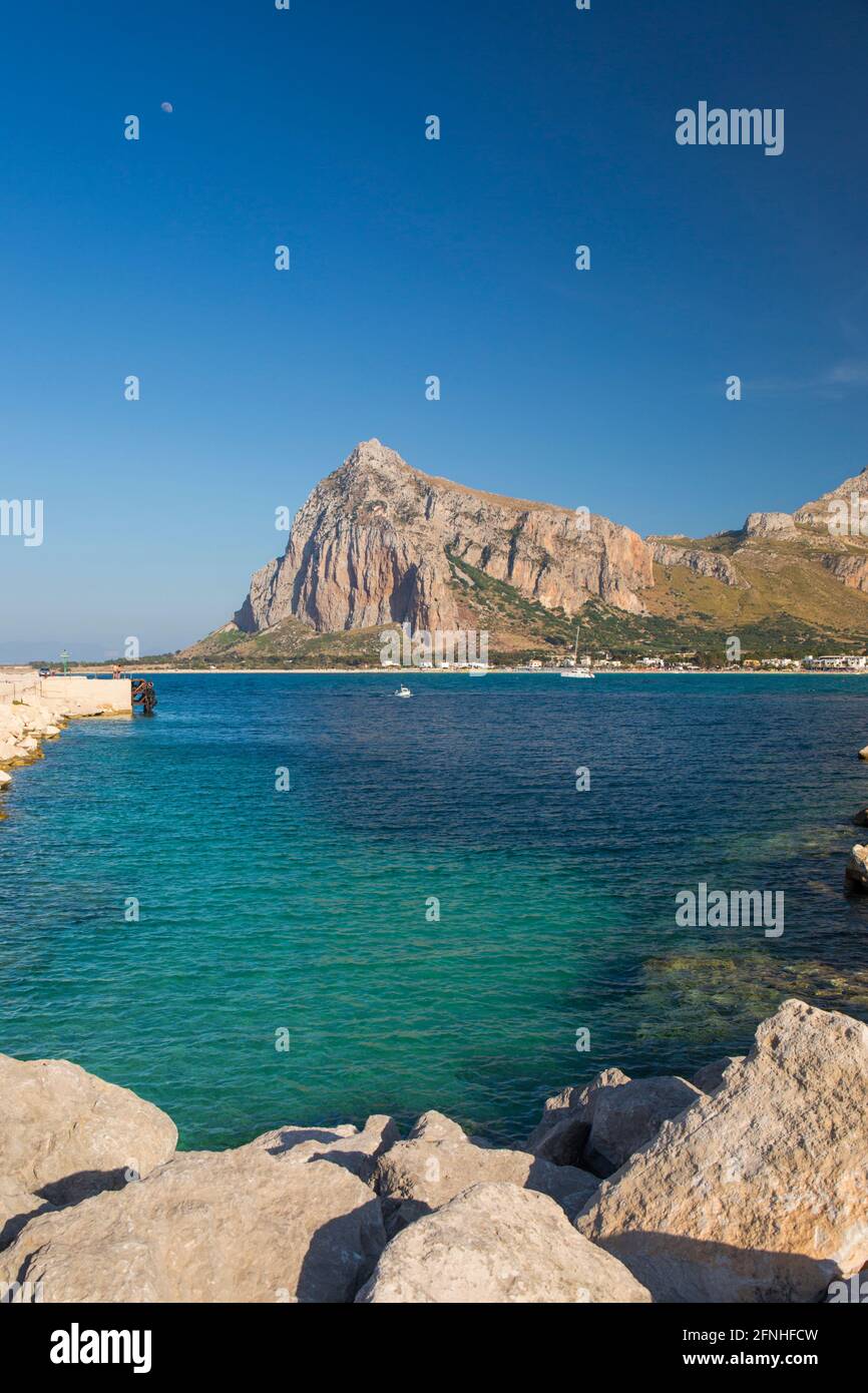 San Vito Lo Capo, Trapani, Sicily, Italy. View from breakwater across clear turquoise water to the towering north face of Monte Monaco. Stock Photo