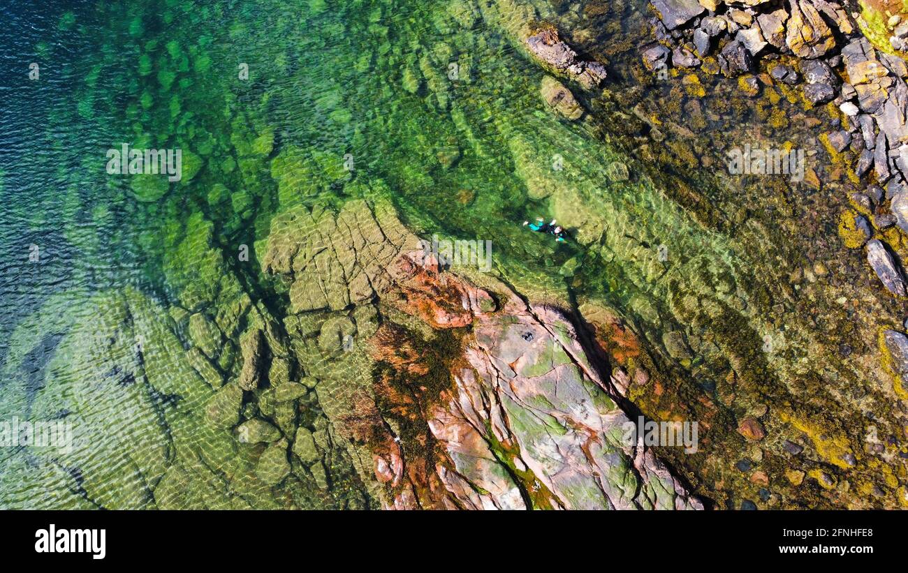 A top down photo of someone swimming in a beautifully coloured rockpool. The contrasting shades of the water, rocks and swimmer make this eyecatching. Stock Photo