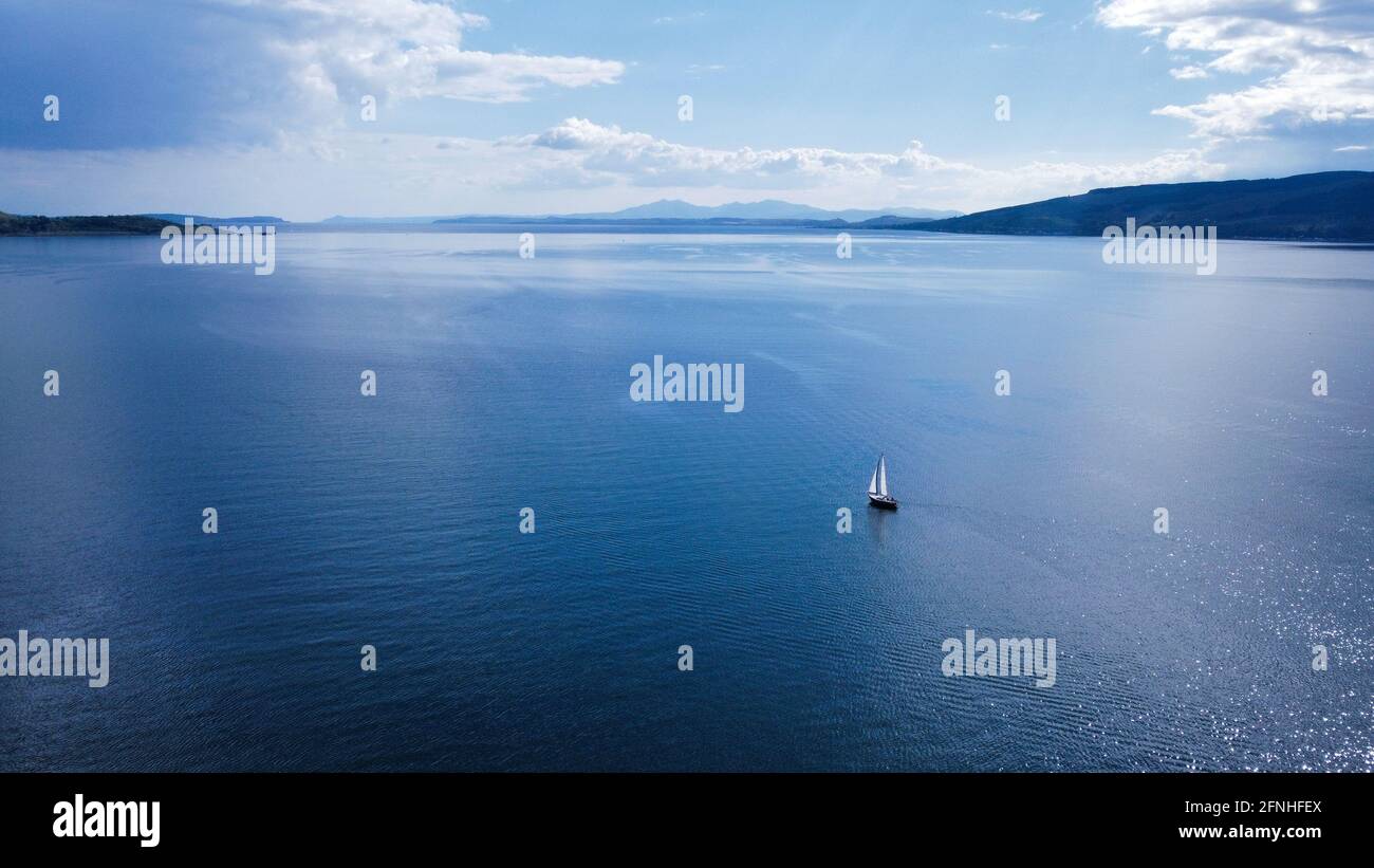 Yacht sailing in the Firth of Clyde. It can be a metaphor or just as a nice picture of a boat sailing into the blue horizon. Multi-purpose photo. Stock Photo