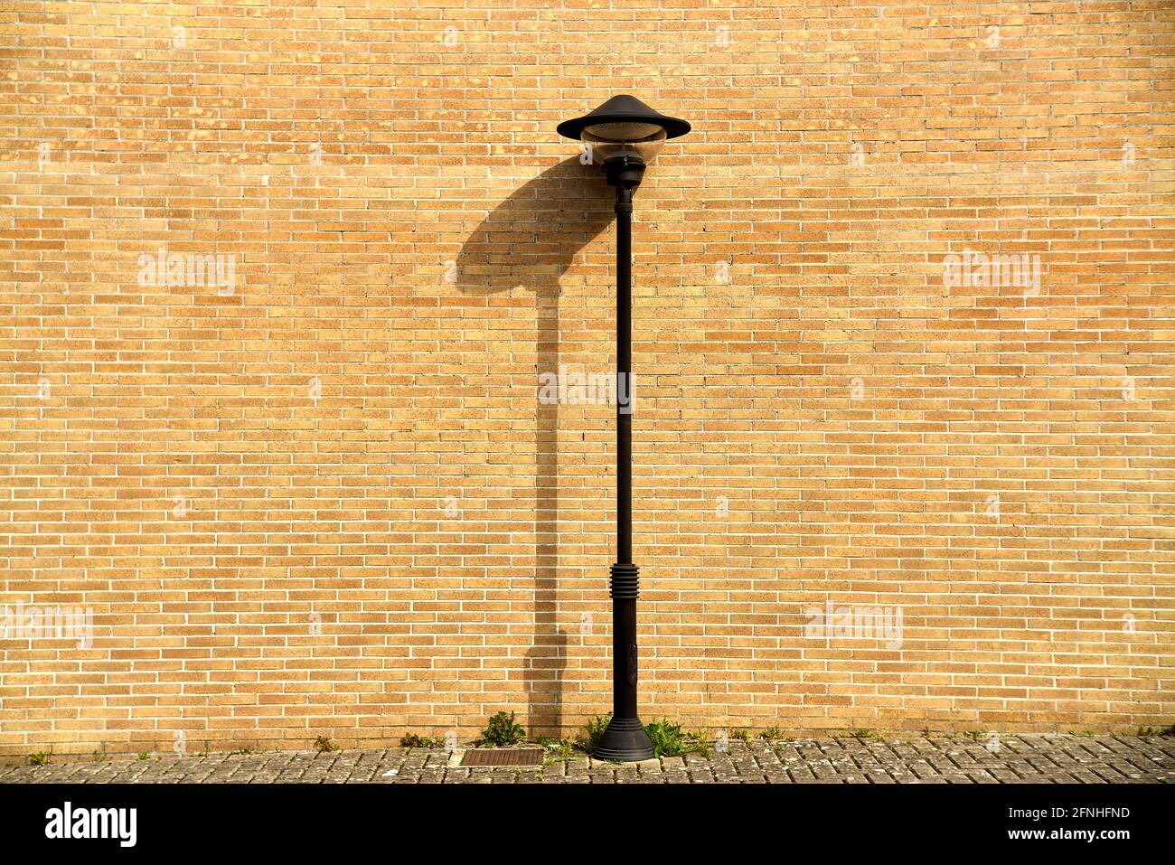 Lonely black lamppost on yellow bricks background Stock Photo