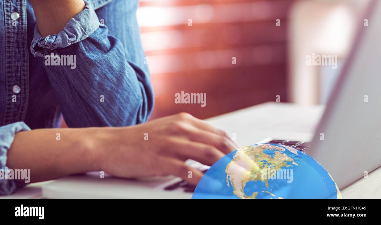 Earth over woman working at a computer in the background, global economy concept Stock Photo