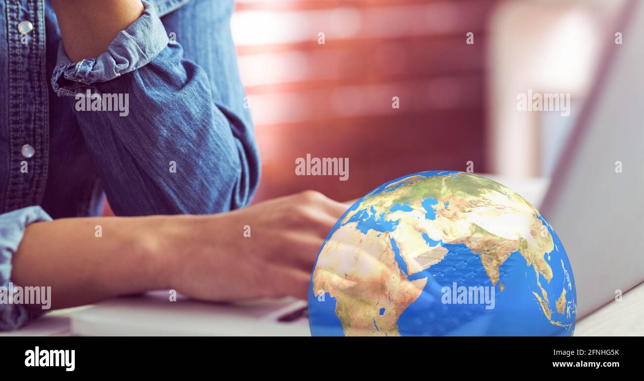 Earth over woman working at a computer in the background, global economy concept Stock Photo