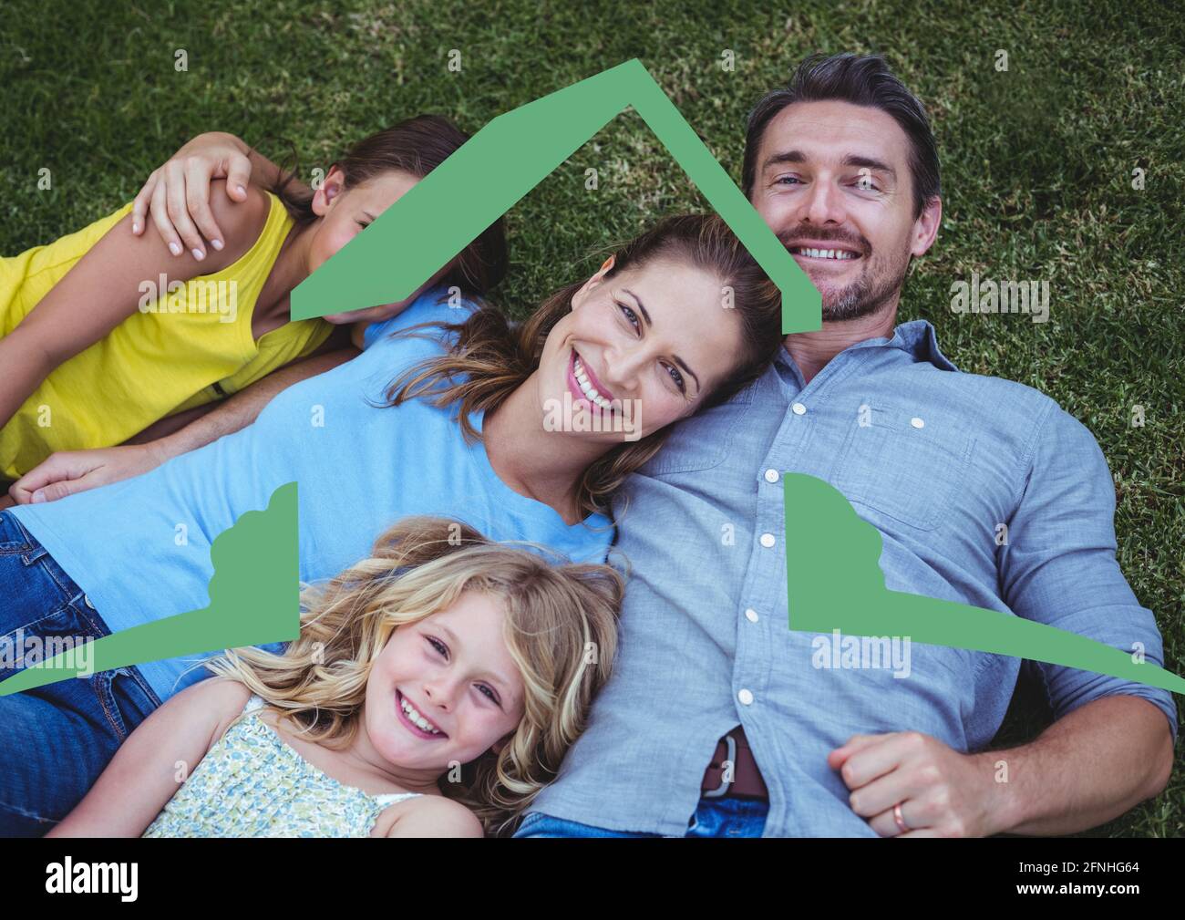 Happy caucasian family relaxing in the grass with home symbol Stock Photo