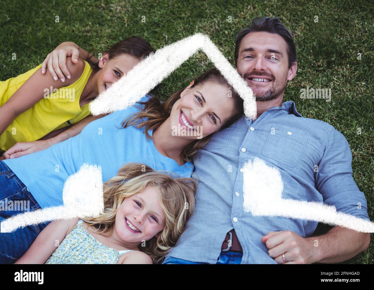 Happy caucasian family relaxing in the grass with home symbol Stock Photo