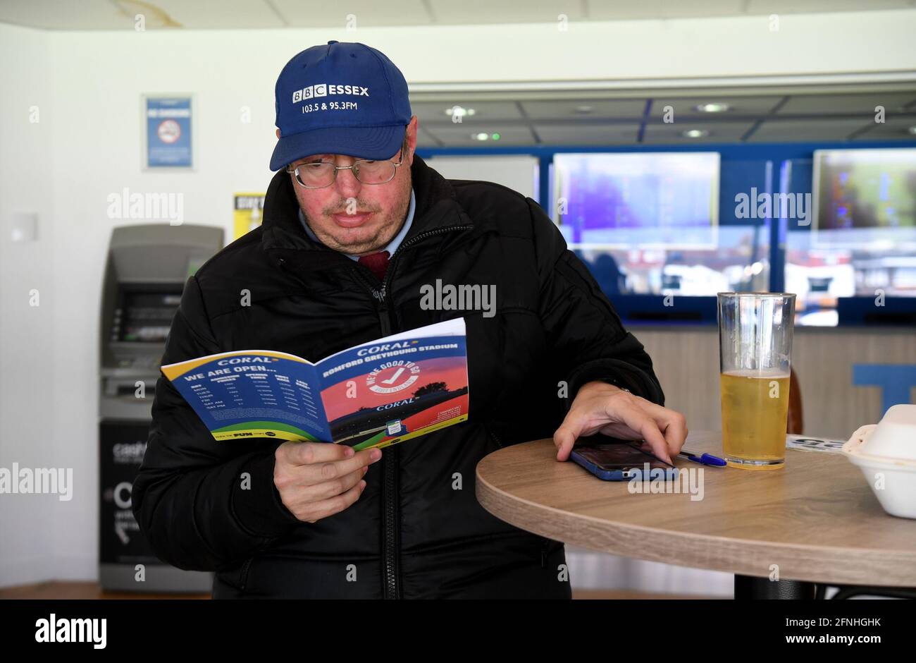 A spectator reads the racecard at Coral Romford Greyhound Stadium, Romford. Picture date: Monday May 17, 2021. Fans return to sporting events following the further easing of lockdown restrictions in England. Stock Photo