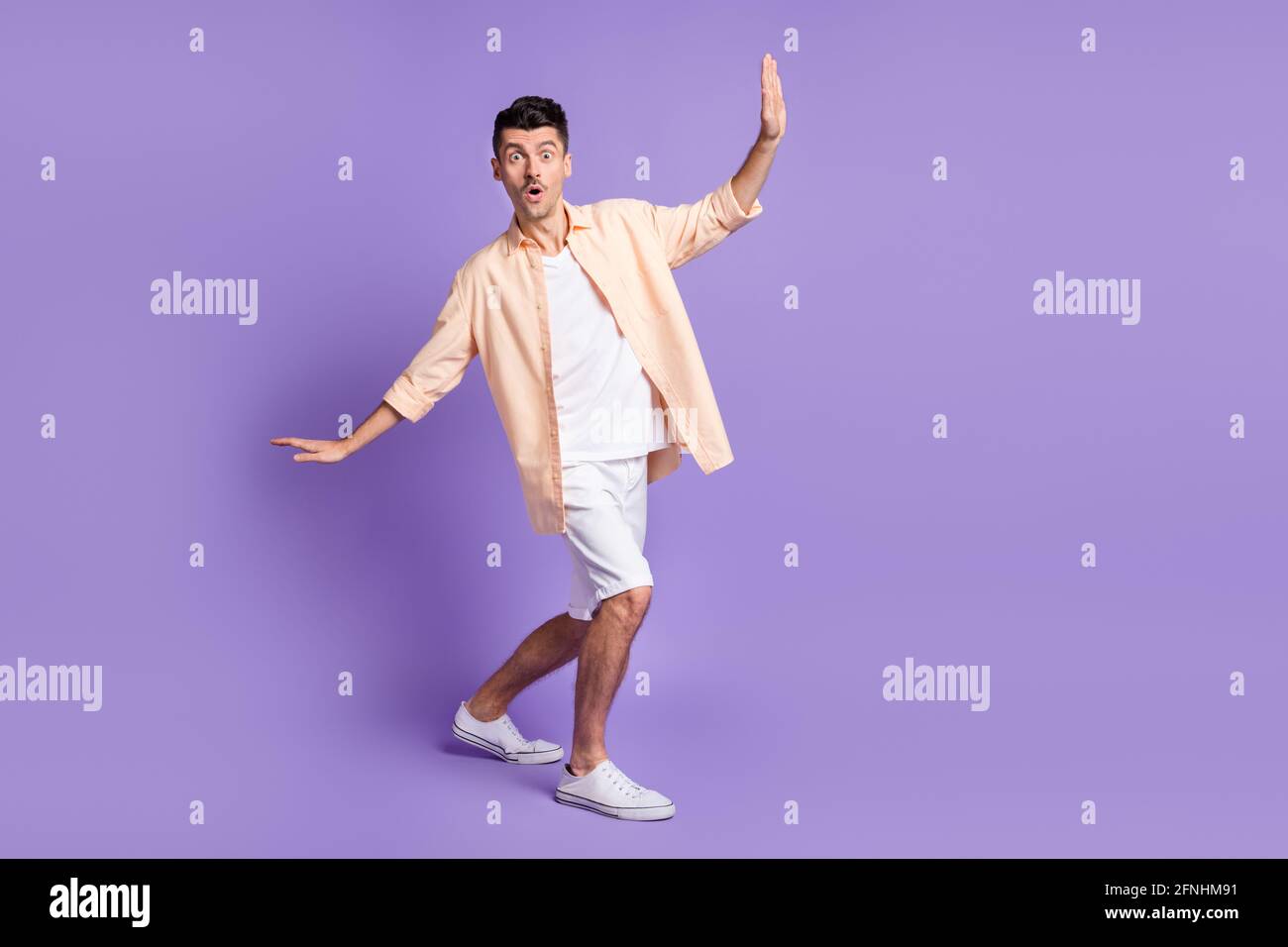 Photo of shocked young guy dance having fun look camera wear beige shirt isolated violet color background Stock Photo