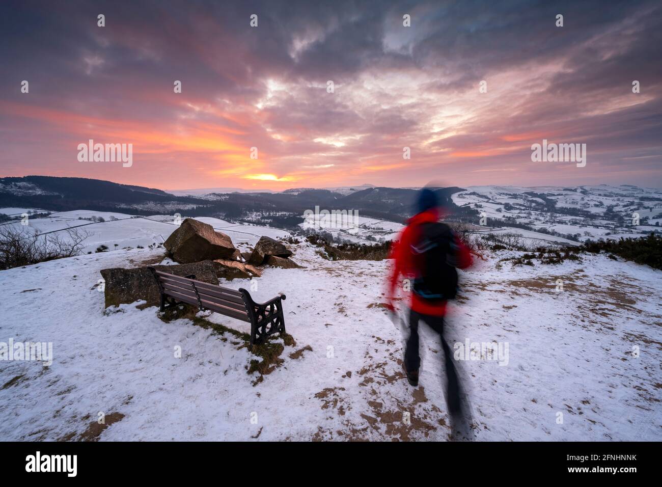 Man walking towards spectacular sunrise over Shutlingloe and Macclesfield Forest, Teggs Nose, Cheshire Stock Photo