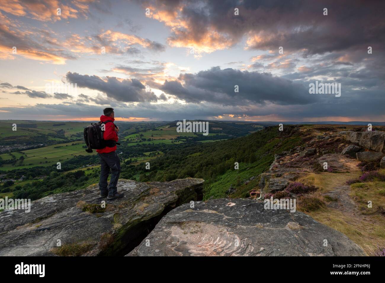 A walker stood looking at an Incredible sky above Curbar Edge, Derbyshire Stock Photo