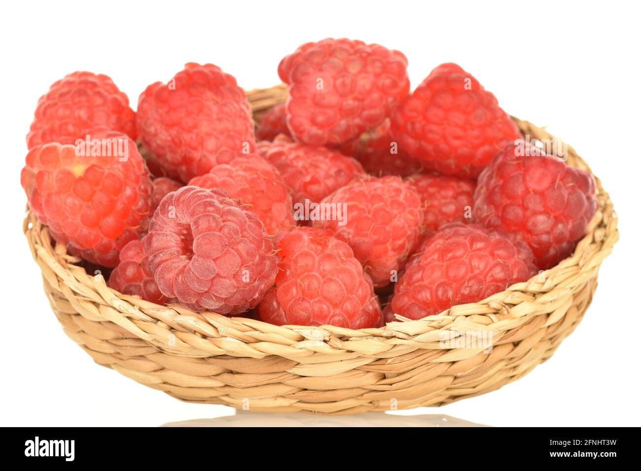 Ripe red raspberries in a straw plate, close-up, isolated on white ...