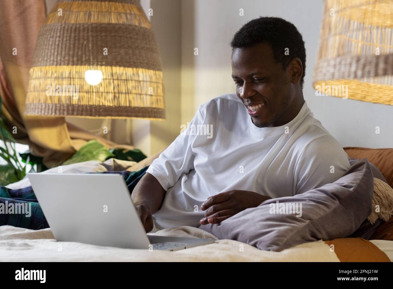 African man surfing the internet in his bed at home Stock Photo