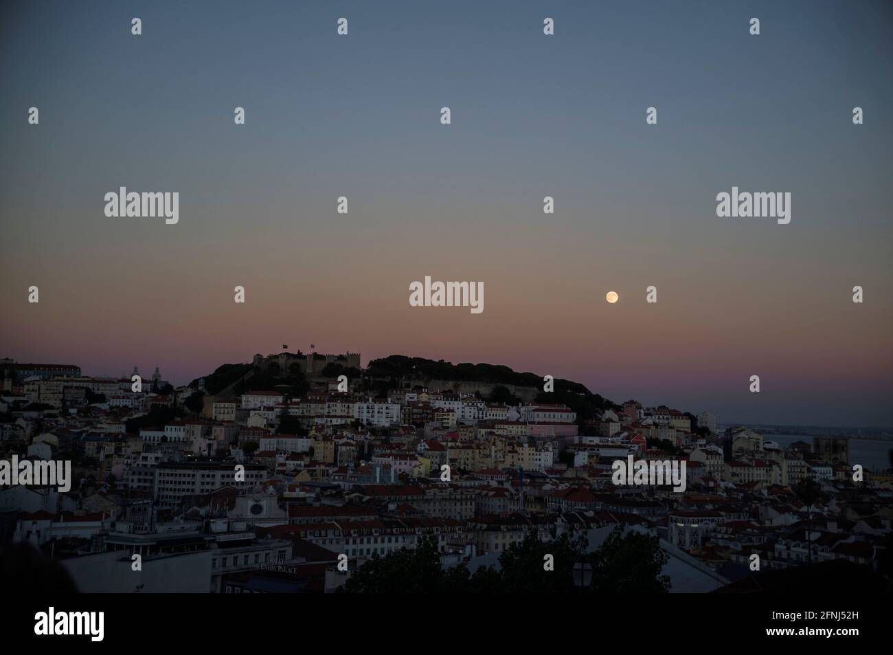 Blick vom Miradouro de São Pedro de Alcântara auf die Viertel Alfama, Mouraria und Graça, sie bilden die Altstadt von Lissabon. Hier mit Mondaufgang Stock Photo