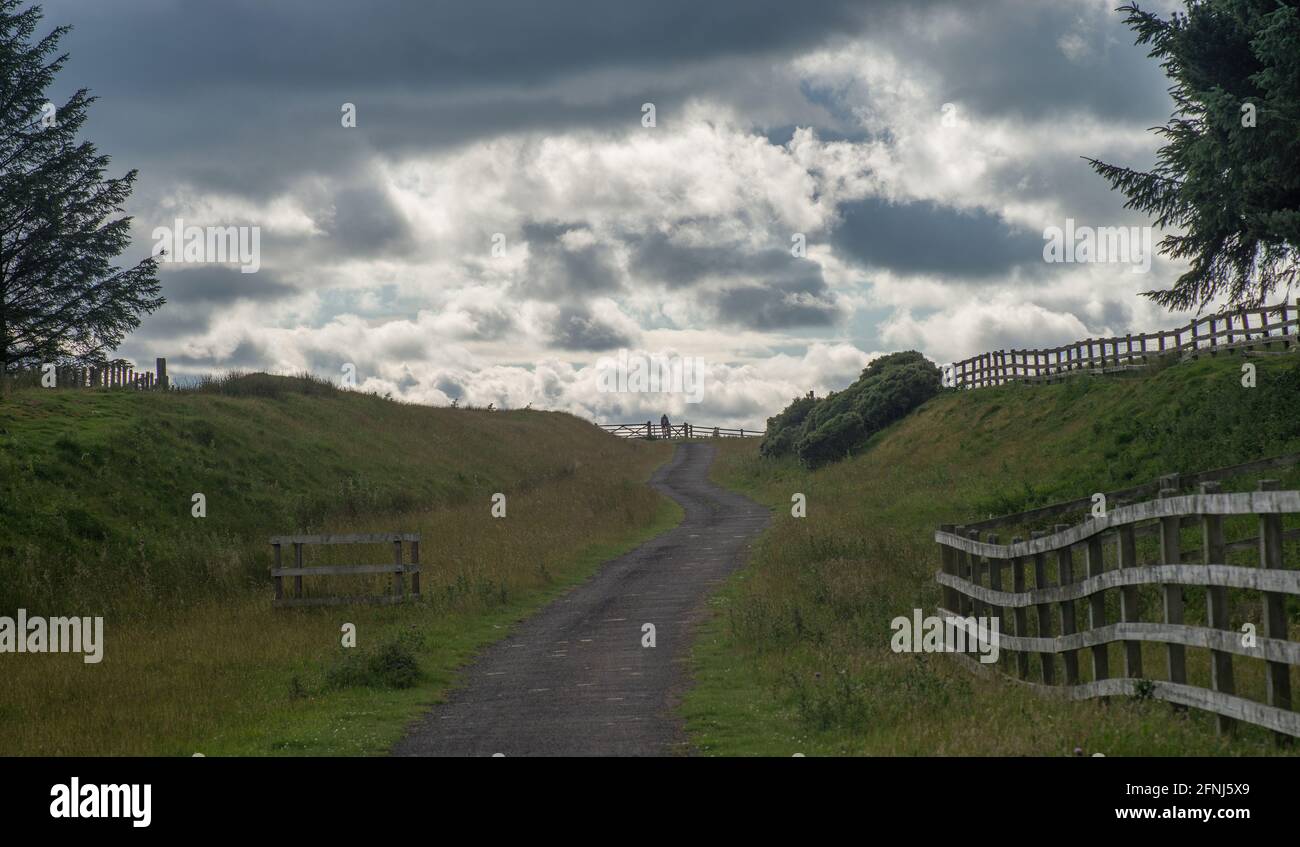 Cyclist coming through gates on an old railway track now used for leisure activities of walking, cycling and horse riding Stock Photo