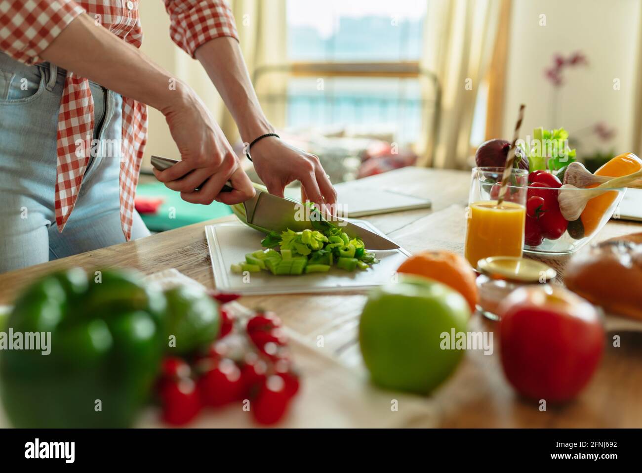 Close-up of the hand only view of a woman slicing a salad, preparing for a healthy organic vegetarian meal with chilli peppers and broccoli. On the Stock Photo