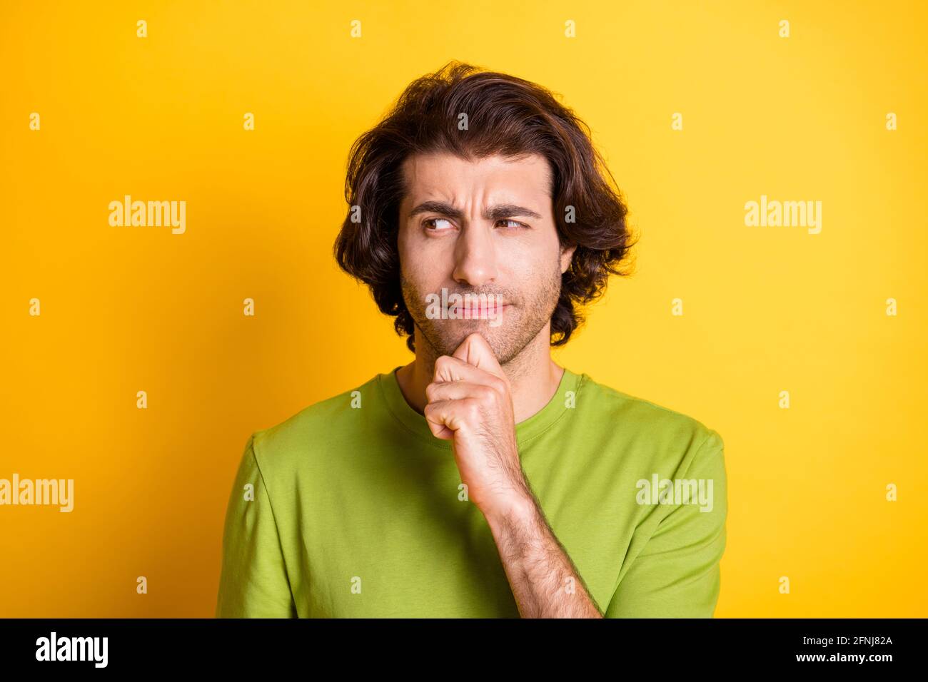 Photo of ponderous smart guy finger chin look side empty space wear green t-shirt isolated yellow color background Stock Photo