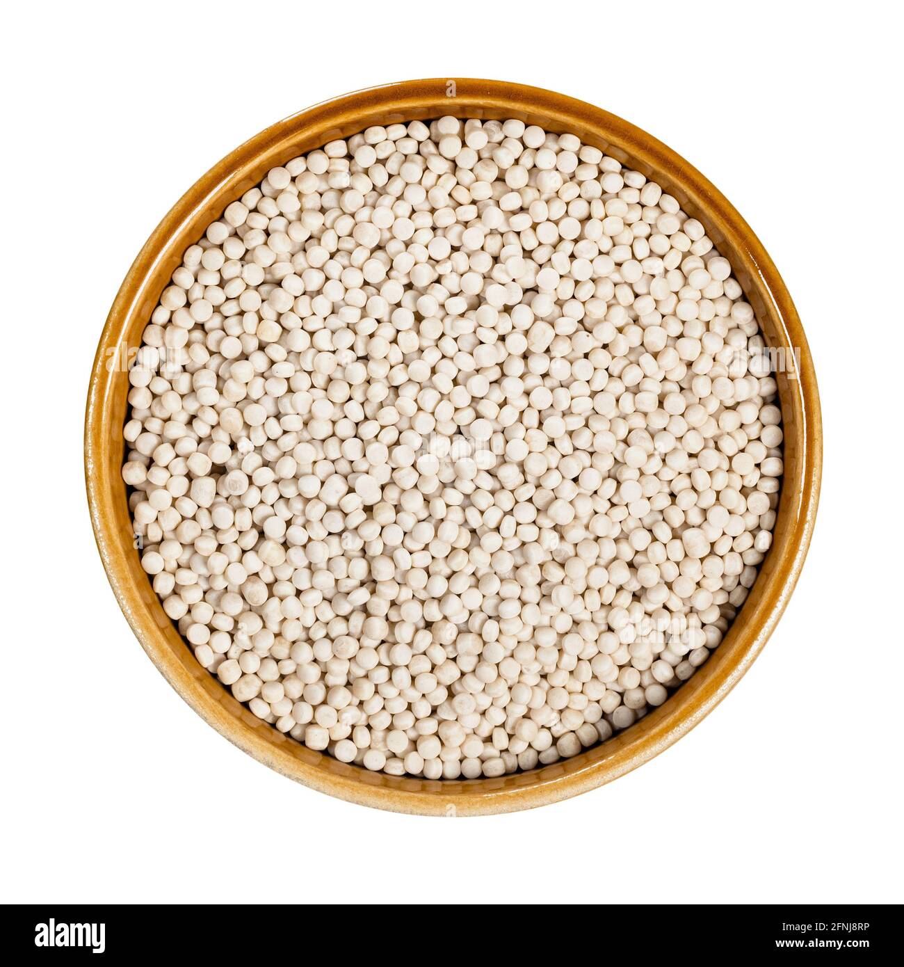 top view of uncooked ptitim (pearl couscous) in round ceramic bowl cutout on white background Stock Photo