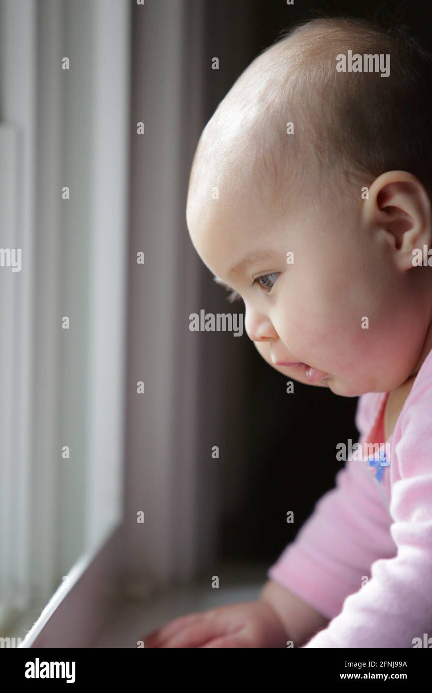 Baby at a window sill looking out into the world. Stock Photo