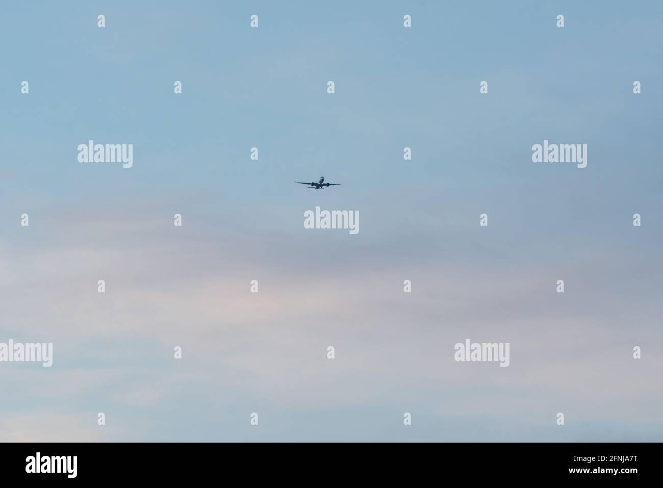 airplane in a blue sky with white clouds Stock Photo - Alamy
