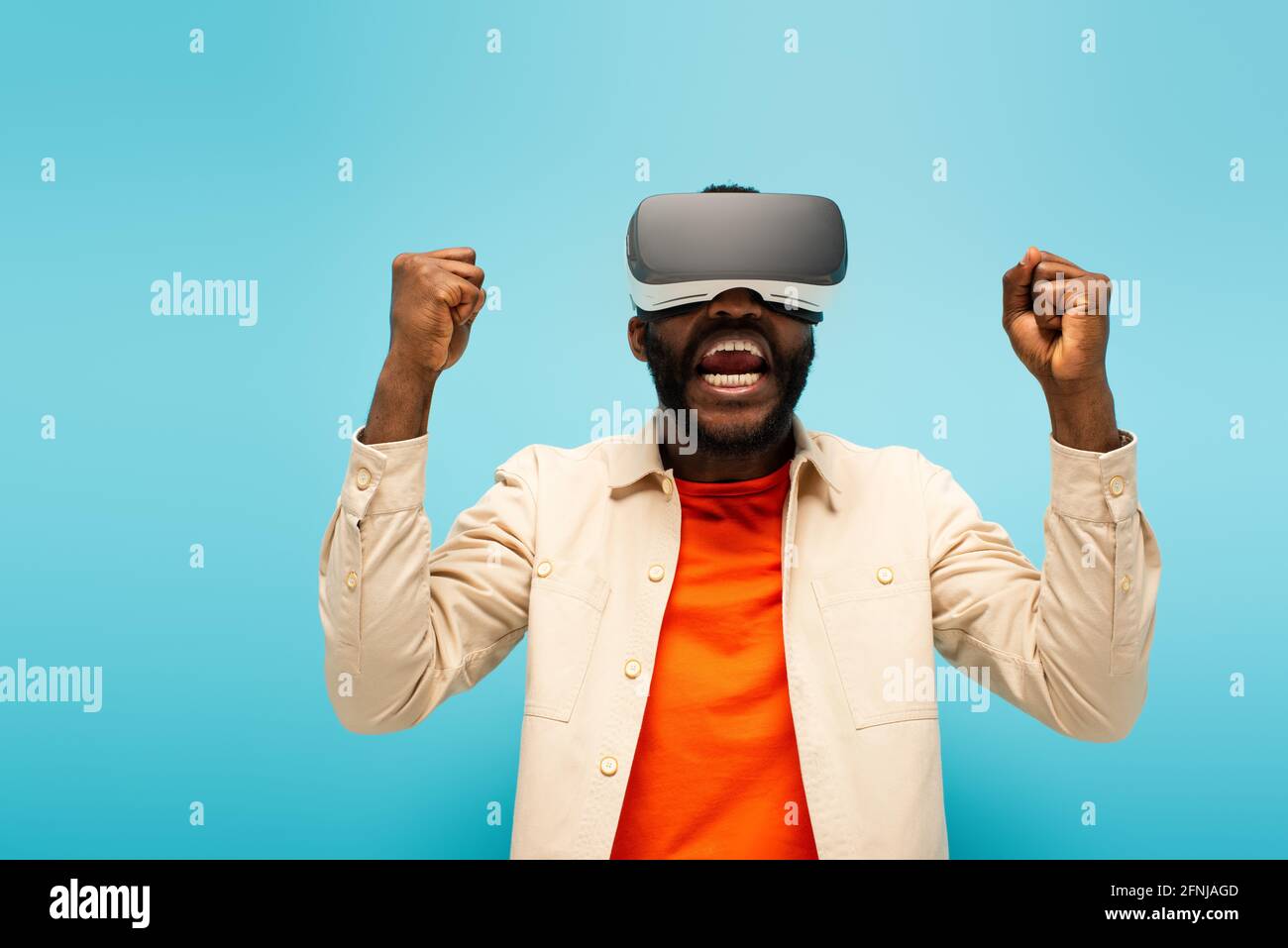 excited african american man in vr headset shouting while showing win ...