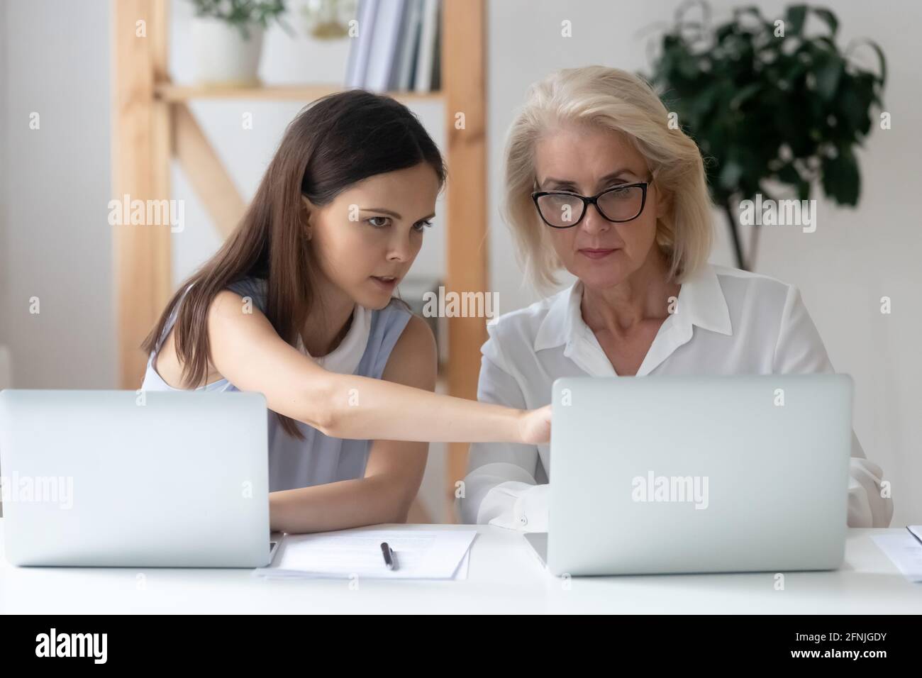 Diverse female colleagues work on laptops brainstorming Stock Photo