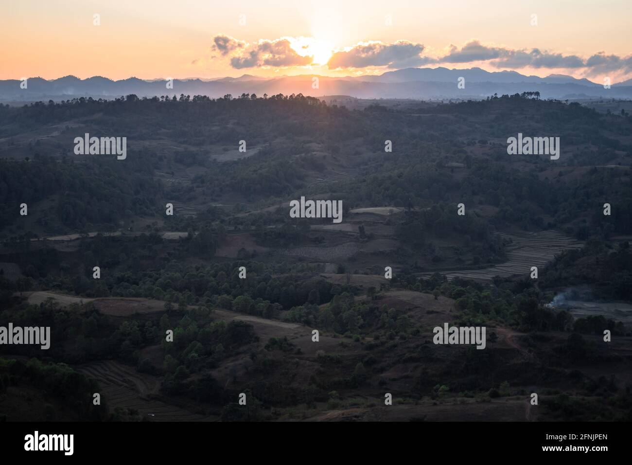 Orange sunset from a viewpoint looking out over the farm lands and hills underneath in a valley between Kalaw and Inle Lake, Shan state, Myanmar Stock Photo