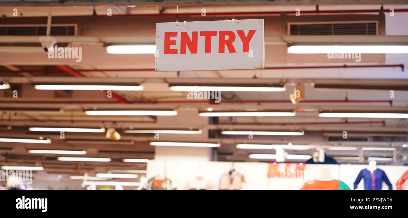 White sign with red letters spelling "entry" in a clothing shop Stock
