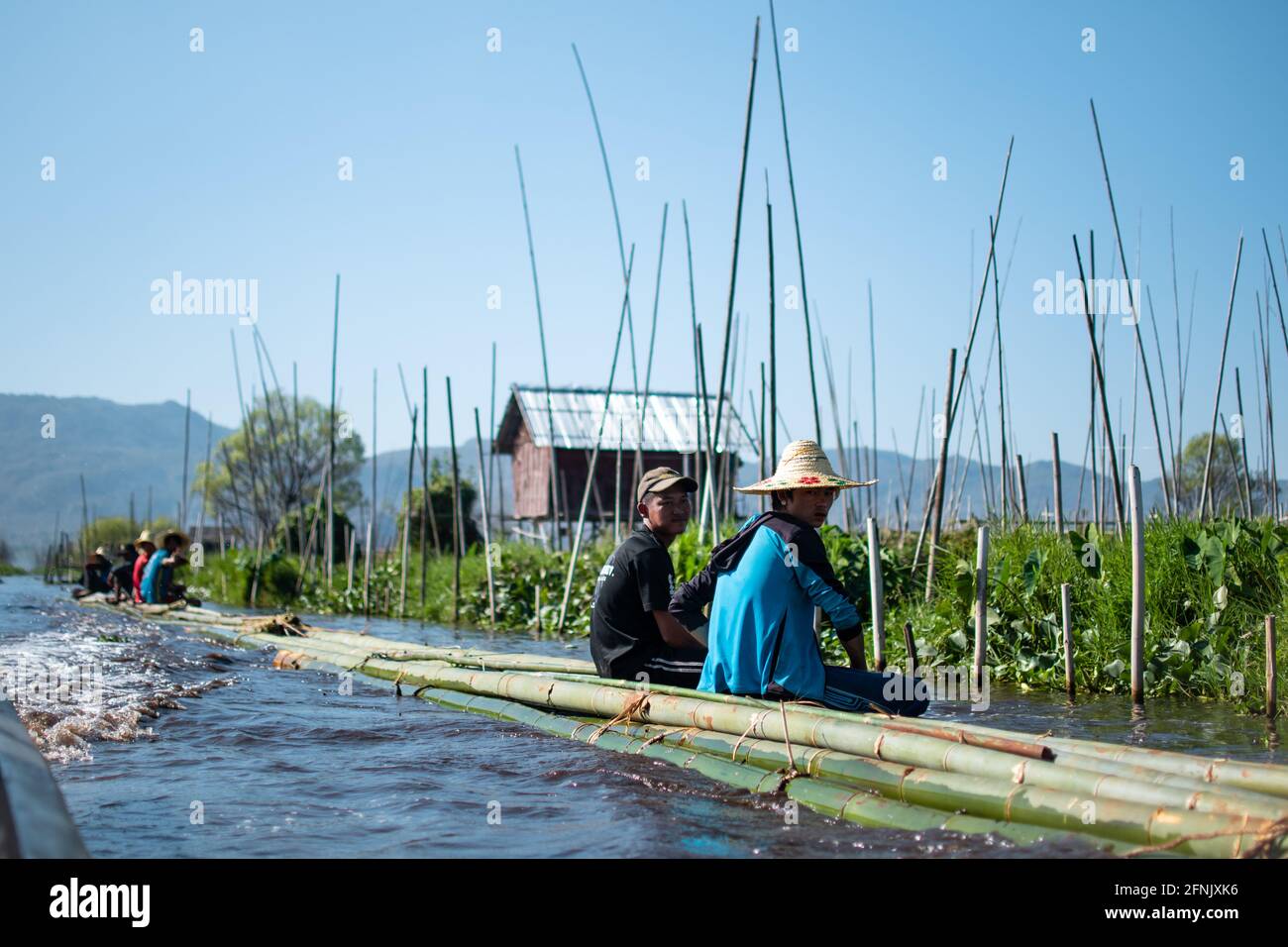 Shan state, Myanmar - January 7 2020: Locals sits on bamboo and floating down a river tugged by a boat at Inle Lake, Nyaung Shwe Stock Photo