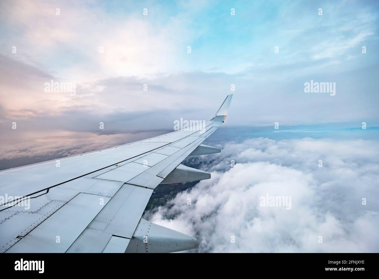 view of aircraft wing in flight over clouds with sunset Stock Photo